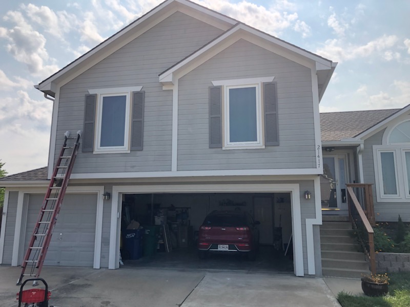 Front of a two-story home with gray siding and brown shutters before repainting