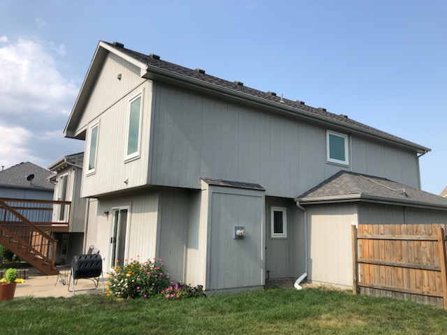 Rear elevation of the same home in weathered gray siding before repainting